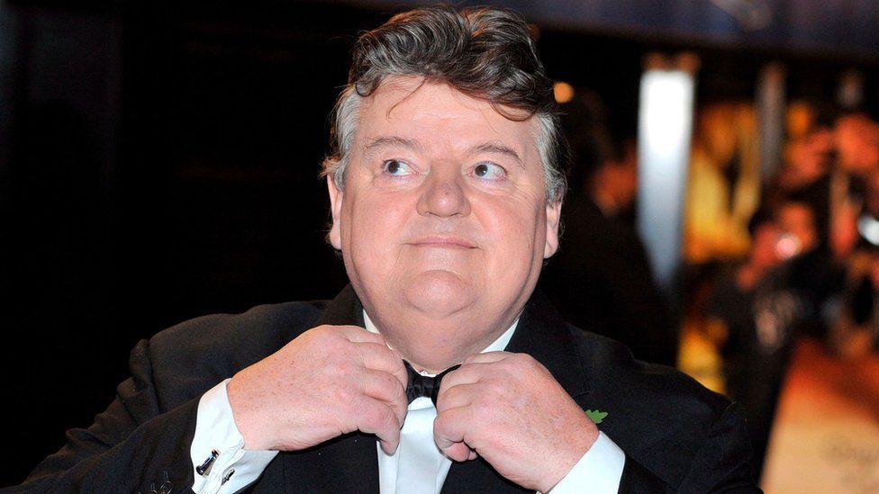 Anthony Robert McMillan OBE (30 March 1950 – 14 October 2022), known professionally as Robbie Coltrane, was a Scottish actor. He gained worldwide recognition in the 2000s for playing Rubeus Hagrid in the Harry Potter film series. He was appointed an OBE in the 2006 New Year Honours by Queen Elizabeth II for his services to drama. In 1990, Coltrane received the Evening Standard British Film Award – Peter Sellers Award for Comedy. In 2011, he was honoured for his "outstanding contribution" to film at the British Academy Scotland Awards. Photo Credit: Getty Images